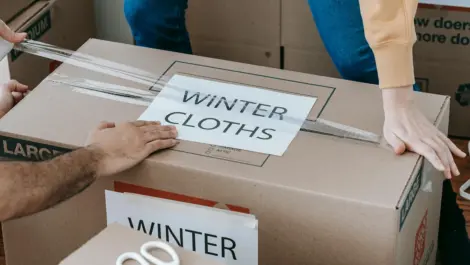 People taping storage box with "winter clothes" sign.