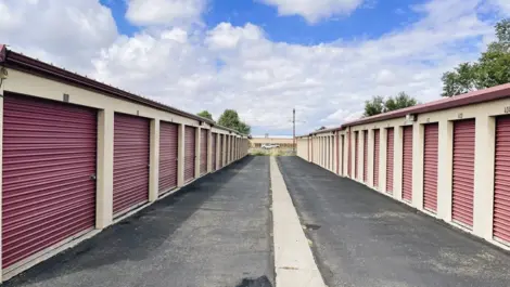 Outdoor storage units with wide paved aisle at Alice's Attic Self Storage facility.
