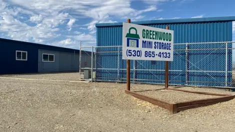 Exterior of Greenwood Mini Storage with fenced perimeter and storage units inside.