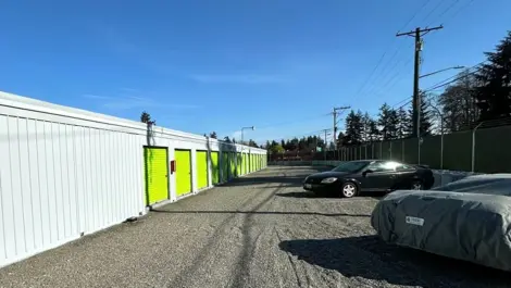Gravel lot with uncovered parking spaces and outdoor units at Sales Road Storage facility.