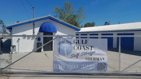 Fence with banner and storage units behind it at Gulf Coast Self Storage Sherman Ave.