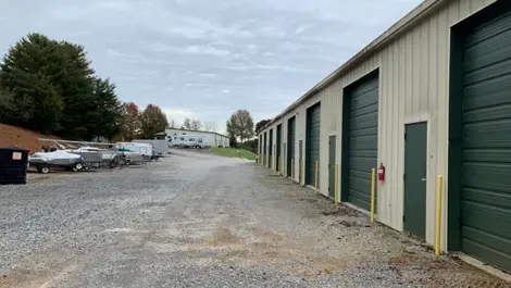 Wide-angle view of storage unit buildings and open gravel lot at Volunteer Storage Tellico Village with vehicle storage in the rear.