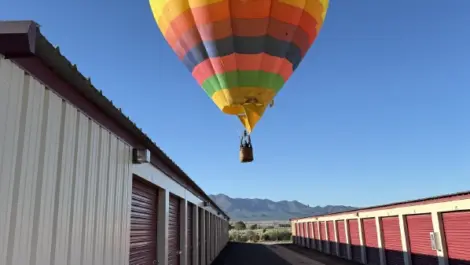 Colorful hot air balloon above Alices Attic Self Storage units on beautiful sunny day