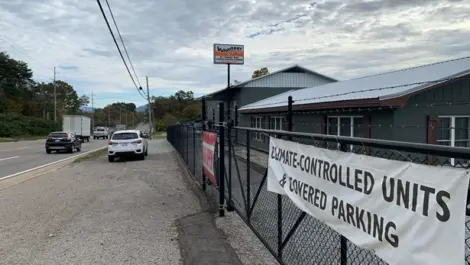 Front view of fenced in Volunteer Storage Maryville 2 storage facility. Banner on fence says "Climate-controlled units & covered parking"