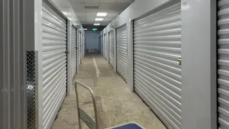 Inside hallway of Ken's Korner Mini Storage with units on each side with cart in the middle.